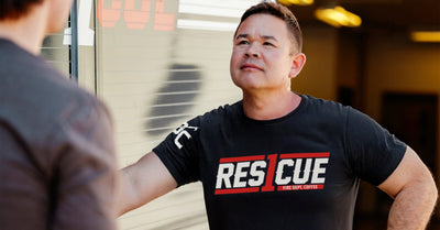 Man standing next to a firetruck wearing a black t-shirt.