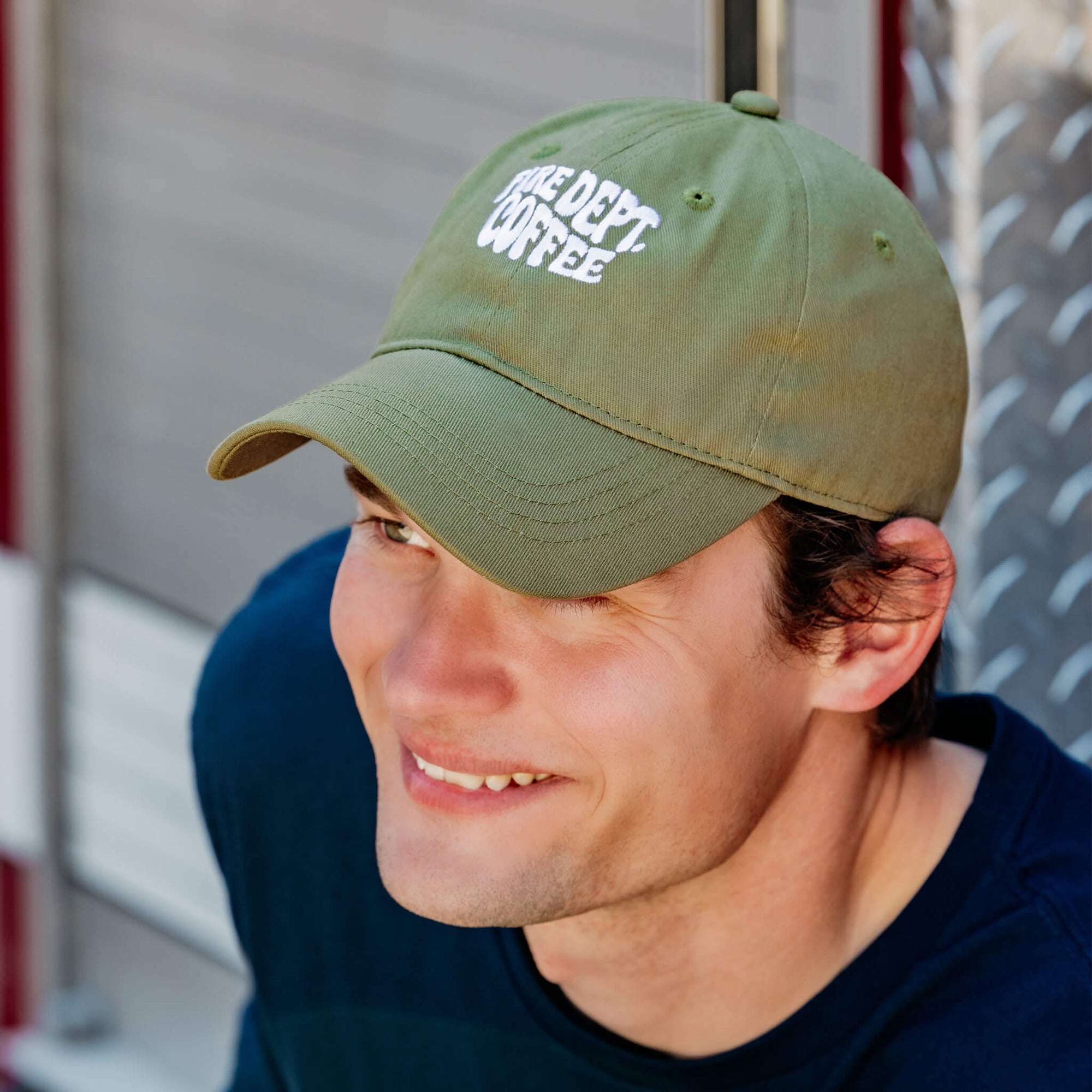 A 3/4 view of the FDC Military Green Groovy Dad Hat, featuring white stitching of Fire Dept. Coffee in a groovy font. 